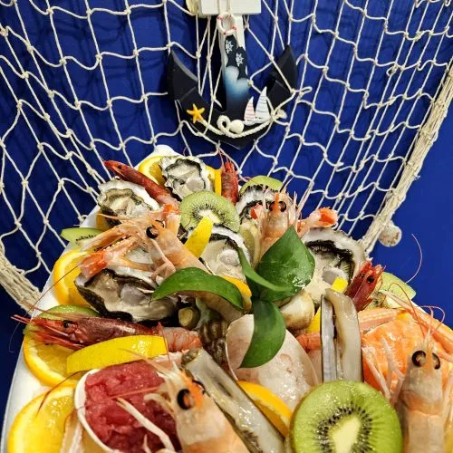 Vassoio di cruditè con ostriche, gamberi e carpacci esposto in pescheria