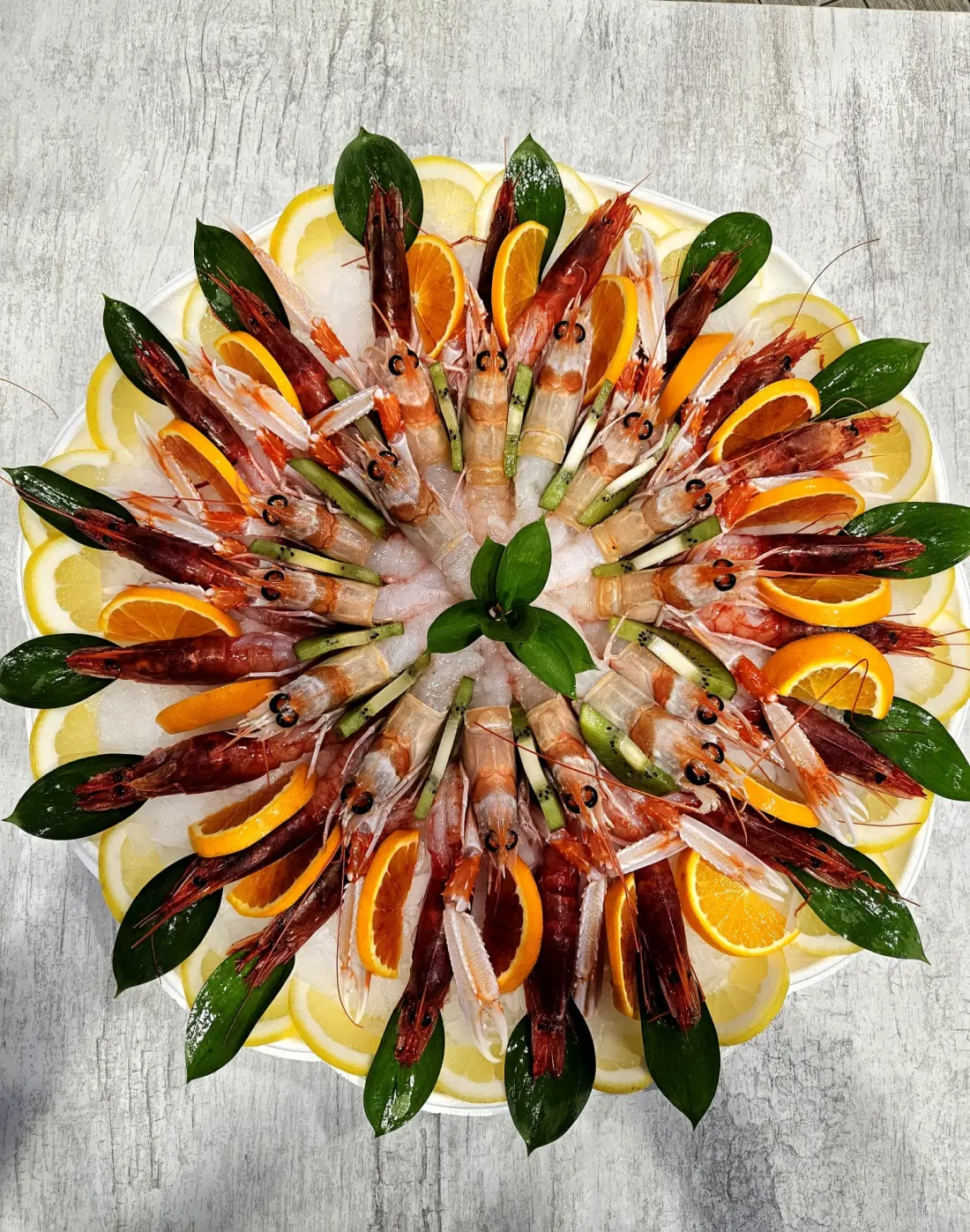 Grande plateau di cruditè con gamberi, scampi e agrumi preparato in pescheria